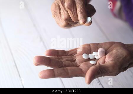 Donna anziana che versa pillole da bottiglia a portata di mano, vista dall'alto Foto Stock