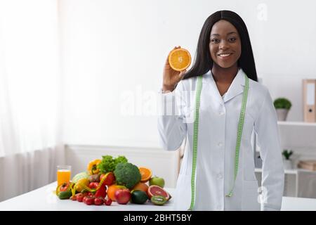 Sorridente signora dietician nero con metro a nastro e arancione Foto Stock