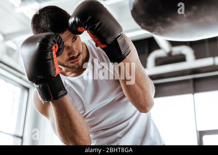 attenzione selettiva dello sportivo nell'addestramento dei guanti da boxe con sacco da punzonatura Foto Stock
