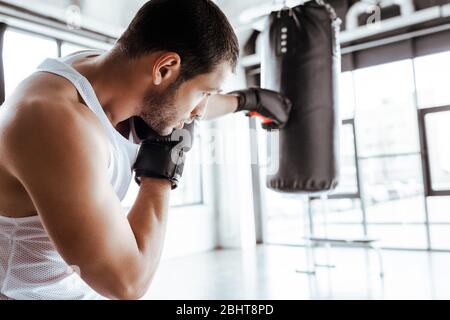 attenzione selettiva dello sportivo atletico in pugilato guanti allenamento con sacco punzonatore Foto Stock