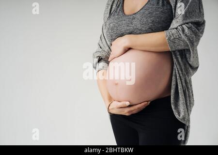 Immagine tagliata di bella donna incinta che tocca il suo ventre Foto Stock