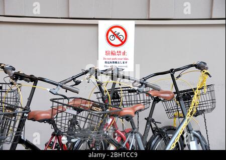 Multilingue senza biciclette Parcheggio Sign in Kyoto, Giappone con biciclette parcheggiate davanti ad esso. Messa a fuoco selettiva sul segno. Foto Stock