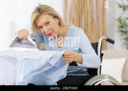 donna in carrozzina ferri a casa Foto Stock