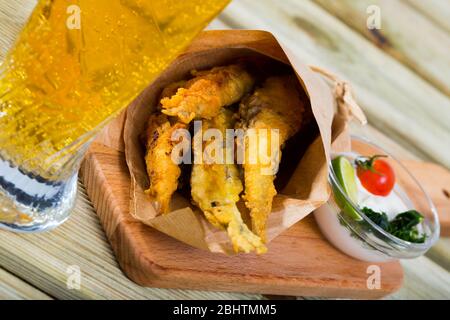 Pesce - patatine fritti in pastella di acciughe con la classica salsa di formaggio cremosa e verdi Foto Stock