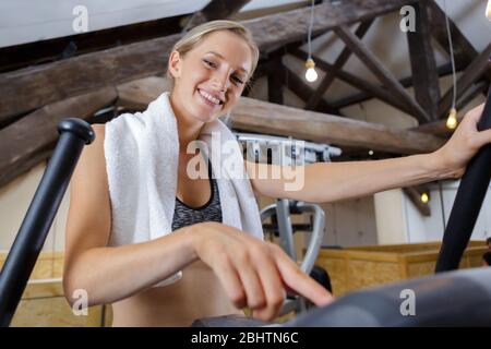 felice bella donna che flette i muscoli sulla macchina da palestra Foto Stock