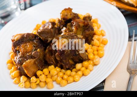 Brasati oxtails con ceci su una piastra bianca Foto Stock