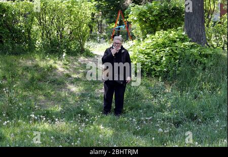 Belgrado, Serbia. 27 aprile 2020. Una donna anziana gode di una giornata calda e soleggiata al parco, tra la perdurante coronavirus COVID-19 pandemic. I cittadini serbi stanno lentamente tornando alla vita normale, poiché le autorità stanno allentando alcune delle misure adottate per limitare la diffusione del coronavirus SARS-cov-2 che causa la malattia di COVID-19. Credit: Koca Sulejmanovic/Alamy Live News Foto Stock