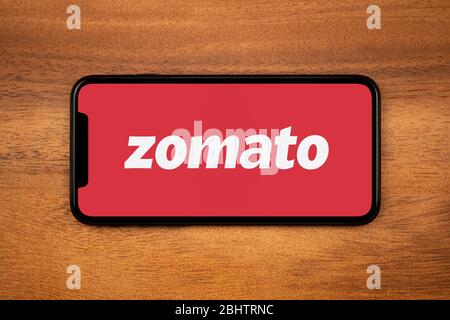 Uno smartphone con il logo Zomato poggia su un tavolo di legno (solo per uso editoriale). Foto Stock