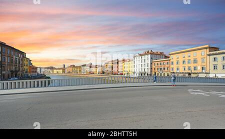 Una coppia gode della vista del tramonto sul fiume Arno nella città di Pisa, in Italia, nella regione Toscana. Foto Stock