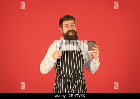 Miglior gusto mai. elegante fiducioso barista maschio bere il caffè. uomo barbuto tenere take away caffè. brutale cameriere cafe. uomo maturo sfondo rosso. Esperti servo. barista hipster chef grembiule. Foto Stock