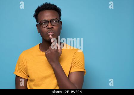 Giovane afroamericano, studente con un dito in bocca nel profondo pensiero Foto Stock