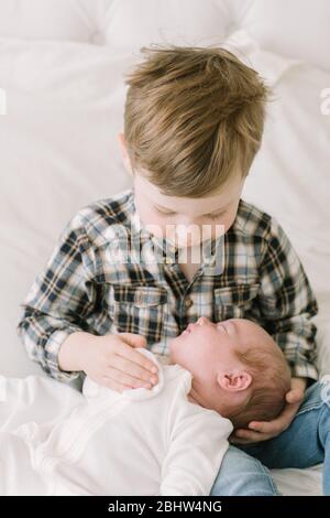 Il fratello maggiore tiene la sorella del bambino per la prima volta a letto Foto Stock