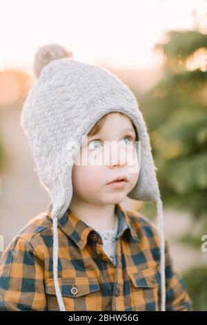 Il bambino che indossa il cappello invernale guarda in su magico, vacanza, premuroso Foto Stock