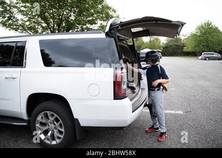 Il ragazzo teen che indossa il casco da baseball carica l'attrezzatura nel SUV dopo Gioco Foto Stock