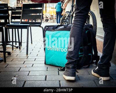 Parigi, Francia - 23 febbraio 2019: Grande piazza Deliveroo piazza thermobag di fronte all'ingresso del ristorante con sedie a sdraio e clienti nelle vicinanze Foto Stock