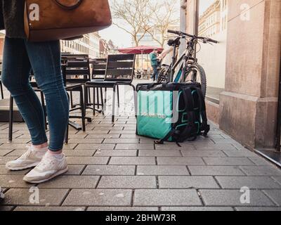 Parigi, Francia - 23 febbraio 2019: Grande piazza Deliveroo piazza thermobag di fronte all'ingresso del ristorante con sedie a sdraio e clienti nelle vicinanze Foto Stock