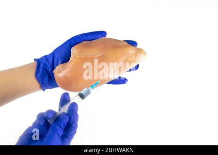 La gente fa siringa di iniezione in filetto di pollo su sfondo bianco Foto Stock