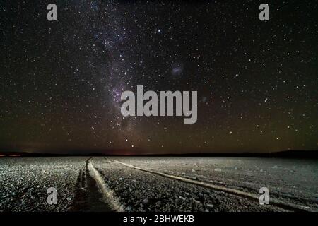 Una vista di una strada sterrata con la pista impresso nella sabbia che va alla Via Lattea in una notte stellata al deserto di Atacama, un'avventura incredibile su un telecomando Foto Stock