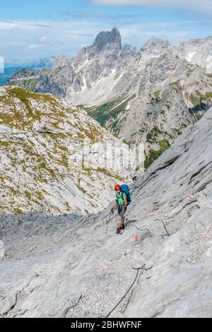 Escursionista su un percorso roccioso assicurato con una corda di filo da Simonyhuette ad Adamekhuette, terreno roccioso alpino, vista del panorama montano e Vorderer Foto Stock