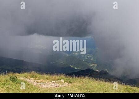 La vista di folte nuvole piovose sopra le montagne. Foto Stock