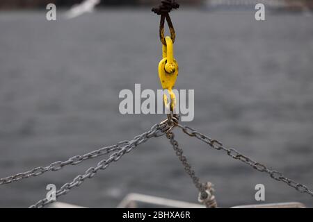 La catena metallica viene utilizzata per il sollevamento dei pesi. Sullo sfondo il mare è sfocato. Foto Stock