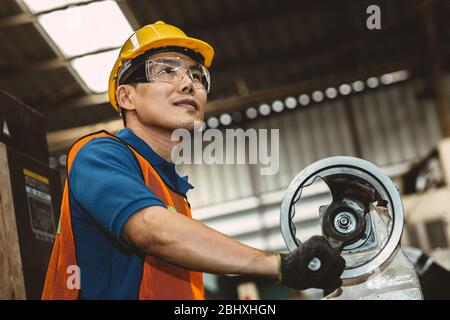 Asian Woker orgoglioso dell'industria pesante che lavora in linea di produzione con felice sorriso in fabbrica. Foto Stock