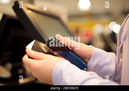 Giovane donna mani chattering fattura per un cliente in centro commerciale enorme, concetto di finanza Foto Stock