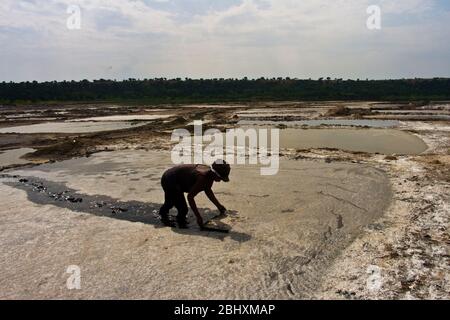 La raccolta di sale dalle padelle di evaporazione nel lago di soda nel cratere di Bunyampaka è un lavoro di ritorno ma un reddito stagionale prezioso Foto Stock