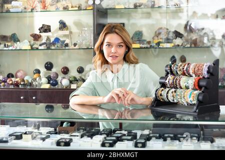 Giovane venditore di successo che dimostra bracciali colorati da diverse pietre preziose in gioielleria Foto Stock