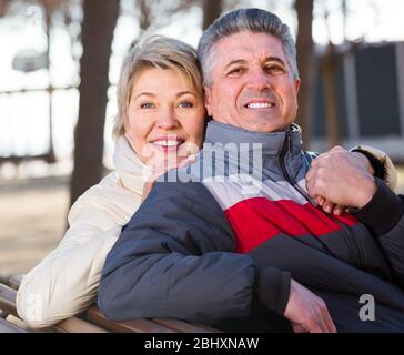 gioiosa coppia sposata matura che tiene le mani l'una l'altra nella giornata di sole nel parco Foto Stock