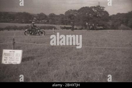 Anni '1950, storia, sport motoristico... un giocatore di corse motociclistiche lungo un campo erboso, scappato dagli spettatori, Inghilterra, Regno Unito. Un avviso su un palo di legno dice che il pubblico non è autorizzato nell'area della concorrenza. Foto Stock