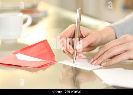 Primo piano di donna mano di scrittura saluto grazie scheda seduto su una scrivania a casa Foto Stock