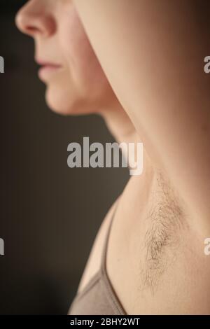 Ascelle femminili pelose e non rasate, su sfondo scuro. Concetto di corpo positivo e l'adozione della sua naturalezza. Foto Stock