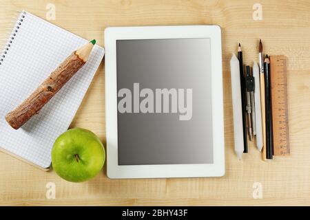 Tablet e forniture scolastiche su tavolo di legno, vista dall'alto Foto Stock