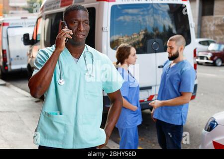 Positivo amichevole sorridente efficiente paramedics con kit di pronto soccorso che va a chiamare dalla vettura ambulanza Foto Stock