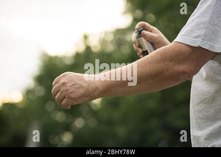 Uomo anziano mani spruzzare zanzara, repellente per insetti nella foresta, concetto di salute Foto Stock