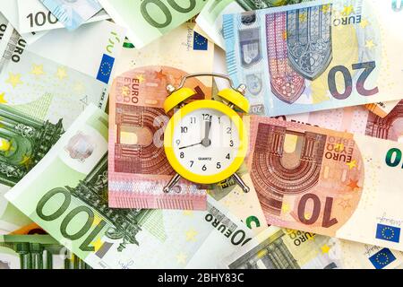 Sveglia con carta euro moneta 10, 20, 50, 100, sveglia su banconote, tempo è denaro Foto Stock