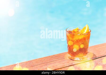 Cocktail Negroni vicino alla piscina presso il bar del resort o il patio della suite. Resort di lusso, vacanza, vacanza, fuga, estate, concetto di servizio in camera. Orizzontale con posto per testo con bokeh festivo e luce del sole Foto Stock