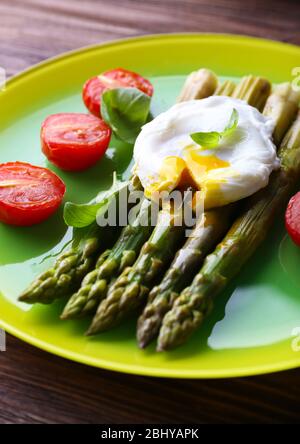 Asparagi arrosto con pomodori e uova in camicia sul piatto da primo piano Foto Stock