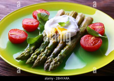 Asparagi arrosto con pomodori e uova in camicia sul piatto da primo piano Foto Stock