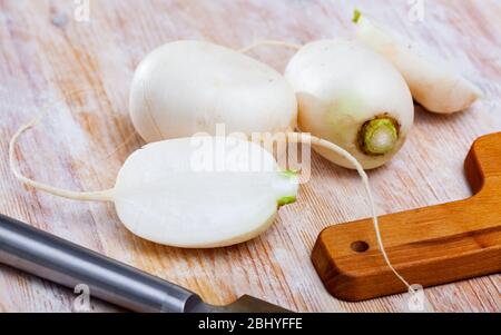 Rape bianche intere e tagliate a fette su tavola di legno. Cibo vegetariano Foto Stock