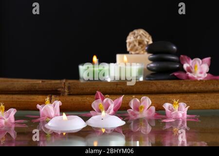 Spa ancora vita con fiori e candele su sfondo nero Foto Stock