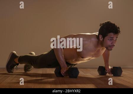 Uomo che fa spadup con manubri su uno sfondo normale. Foto Stock
