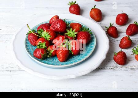 Fragole mature in piastra su sfondo di legno Foto Stock