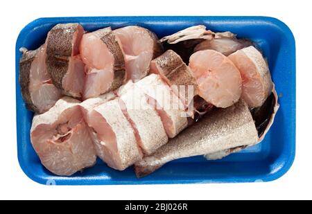 Vista dall'alto delle bistecche fresche di pesce di merlano in un vassoio di plastica blu isolato su sfondo bianco Foto Stock