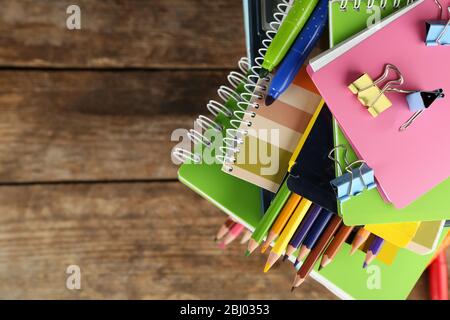 Pila di libri e cancelleria su sfondo di legno Foto Stock