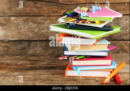 Pila di libri e cancelleria su sfondo di legno Foto Stock