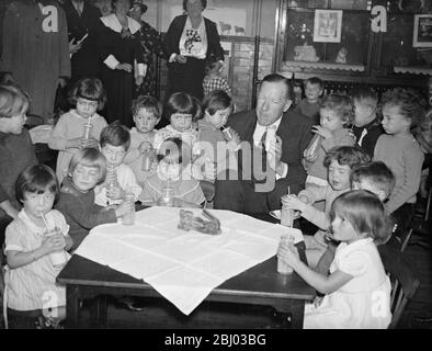 Il sig. Walter Elliot, ministro dell'Agricoltura, beve latte con i bambini presso una scuola londinese. - 1° ottobre 1934 Foto Stock