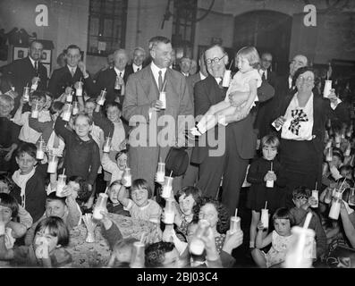 Il sig. Walter Elliot, ministro dell'Agricoltura, beve latte con i bambini presso una scuola londinese. Sig. Elliot e Lord Astor - 1° ottobre 1934 Foto Stock