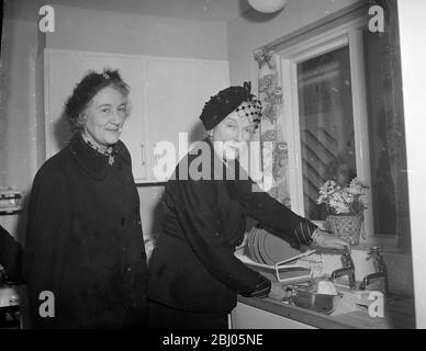 Signora Winston Churchill, moglie del primo Ministro, fa un po' di lavaggio nella cucina della 'Casa dei popoli' alla Ideal Home Exhibition di Olympia. È accompagnata da signora Dorothy MacMillan moglie del ministro dell'alloggio. - 4 marzo 1952 Foto Stock